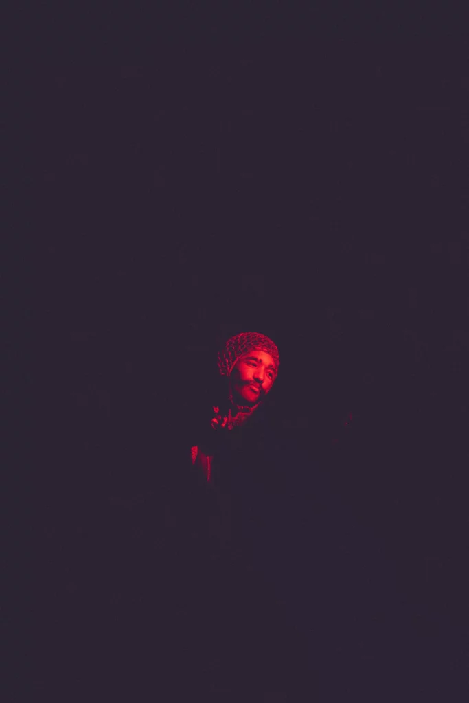 Girls Don't Cry Festival, portrait d'une personne fondue dans l'obscurité, éclairée par une lumière rouge dessinant son visage