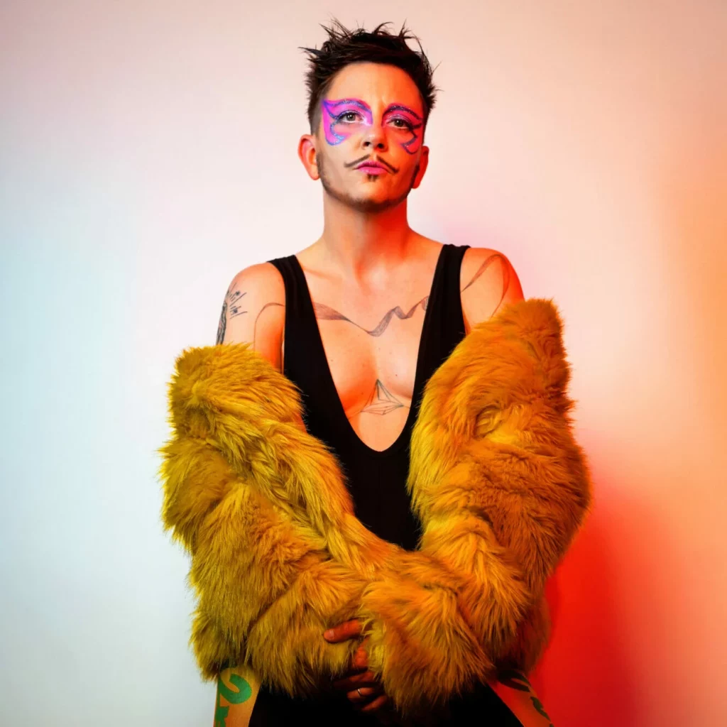Eliott des Adelphes en tenue de scène colorée, maquillage artistique, numéro de cabaret